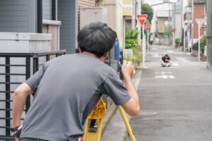 横浜の住宅街で測量機器を使って測量作業を行う土地家屋調査士